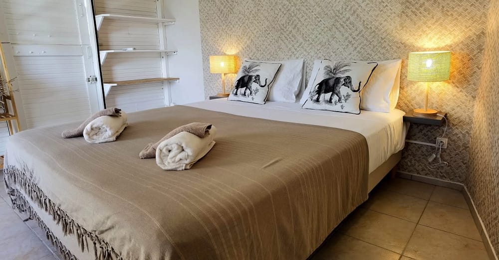 Lit marron avec coussin beiges imprimés éléphant hébergement coco carïb Deshaies Guadeloupe